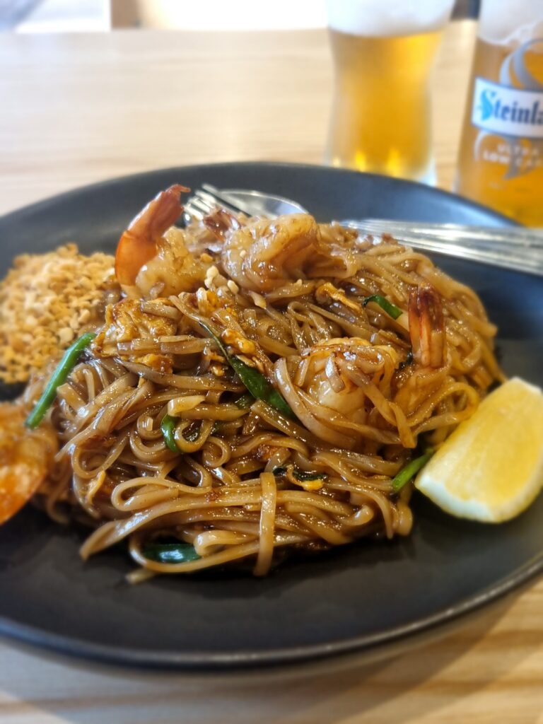 A delicious plate of prawn pad thai, eaten while in Wellington on Te Araroa, with a blurred Steinlager beer in the background. 